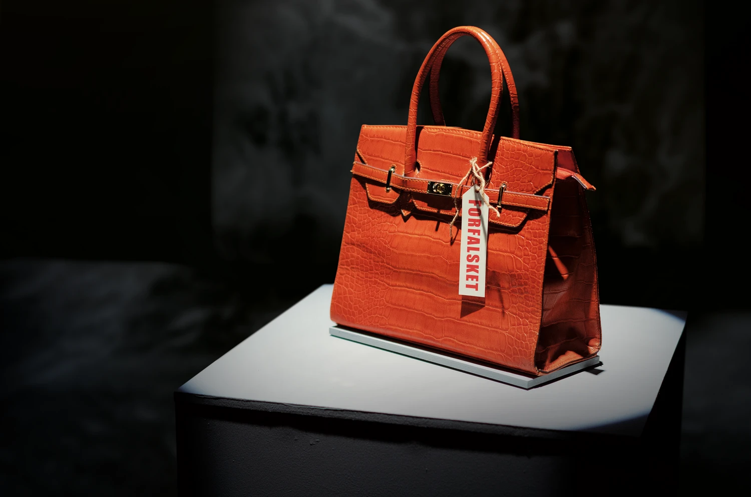 Oransj veske med en lapp det står "forfalsket"